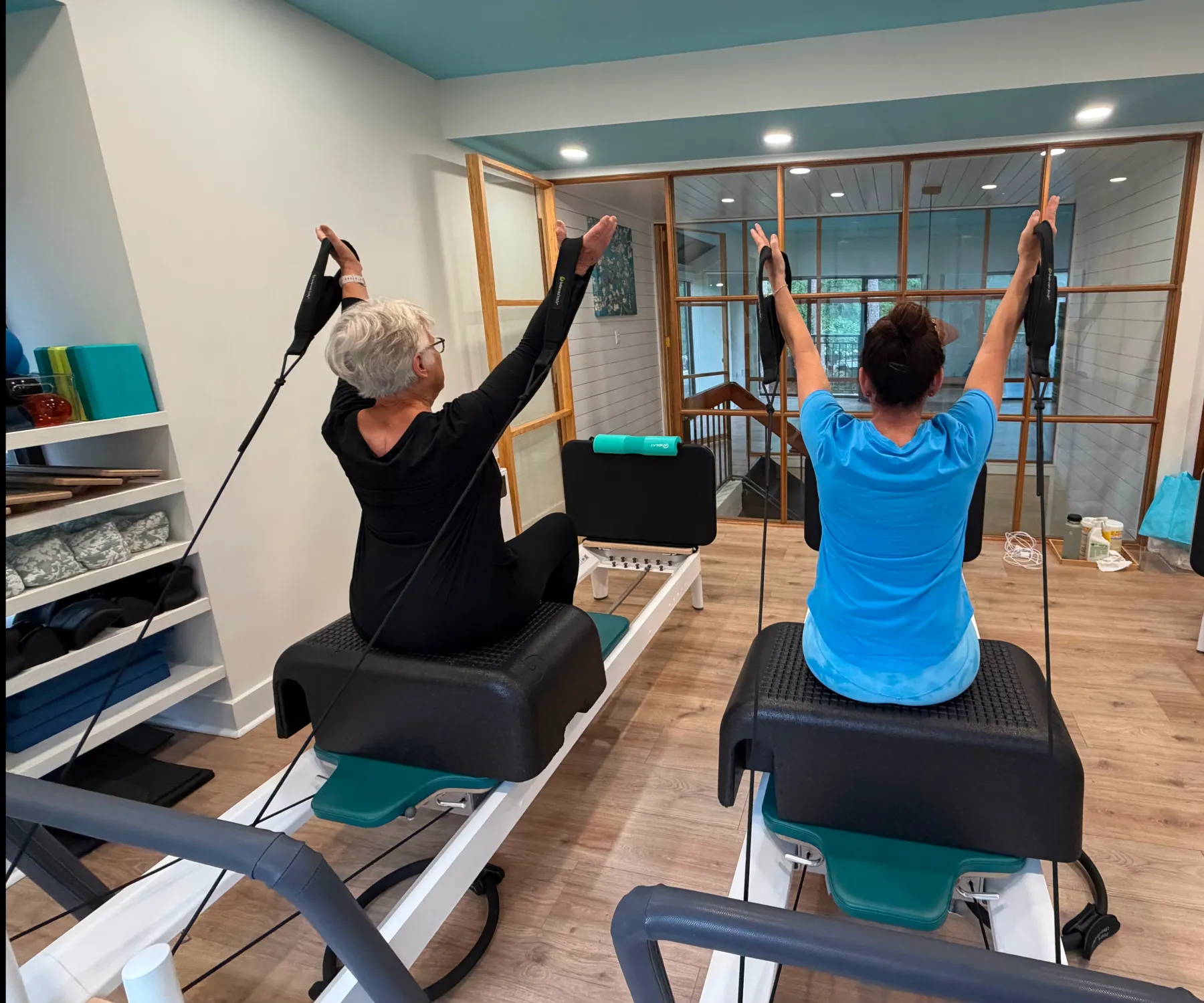 A woman moving through an exercise on a Pilates reformer in the bright, sunlit Blue Sky Pilates studio